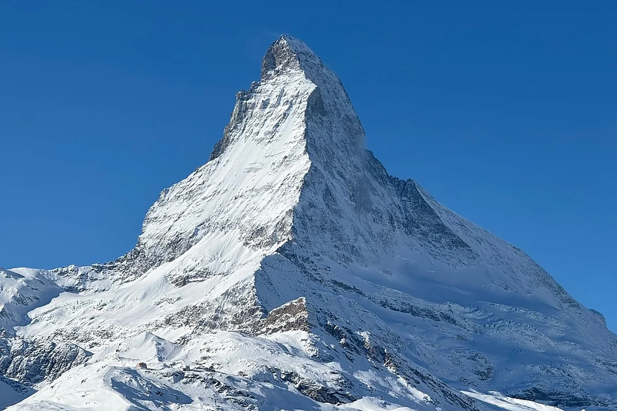 The Matterhorn's distinctive pyramid peak against a clear blue sky, snow catching the morning light.